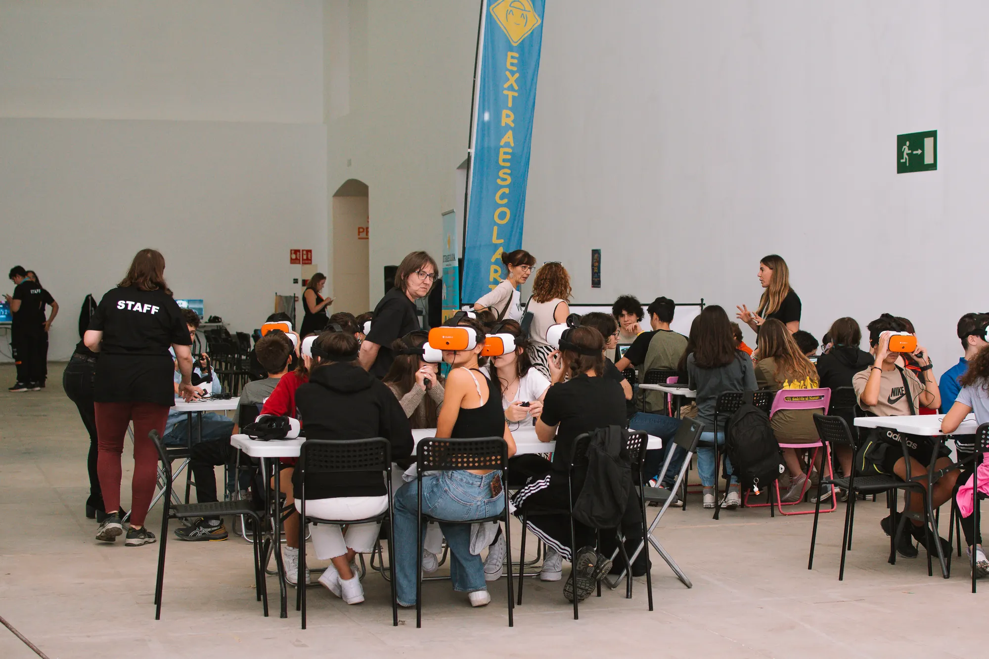 Sala llena durante una jornada tecnológica, con muchas mesas de trabajo en marcha