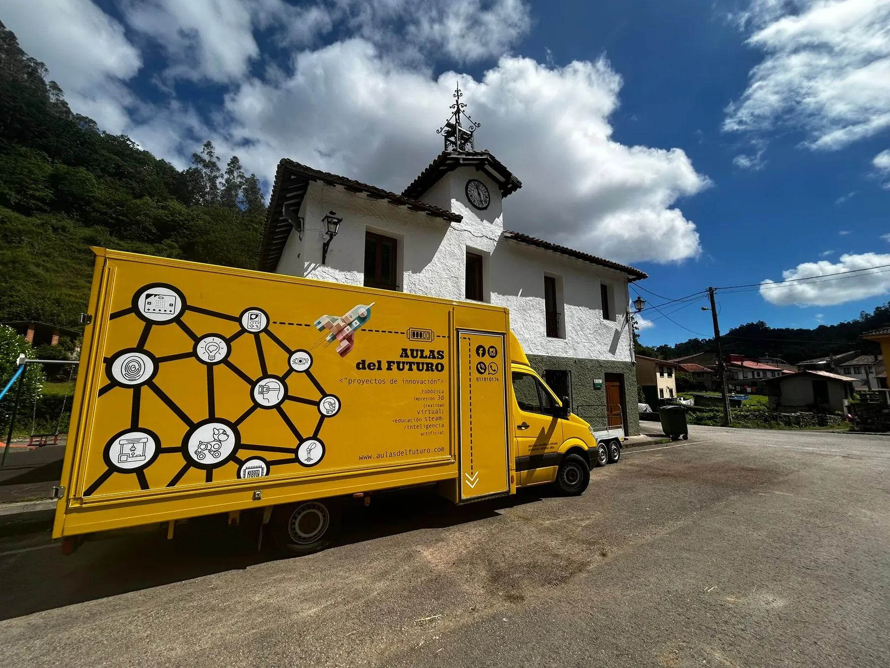El camión STEAM de Aulas del Futuro aparcado frente a la iglesia de un pueblo asturiano