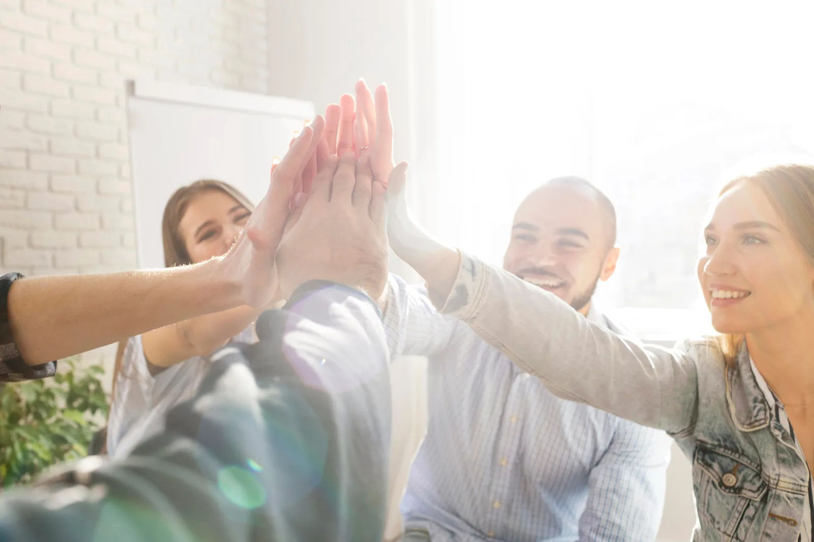 Grupo de adultos chocando las manos durante una actividad de team building en nuestras instalaciones